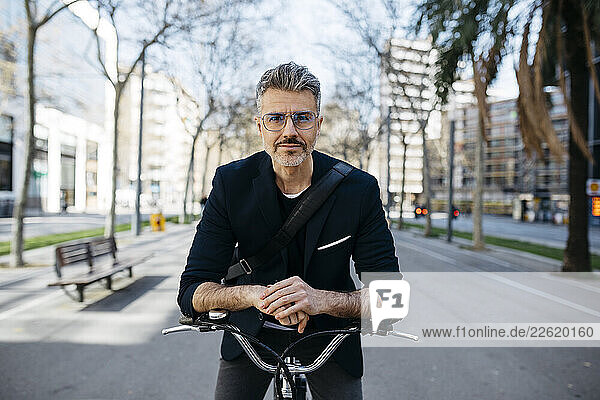 Portrait of a gray-haired businessman with bicycle in the city