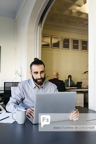 Hipster businessman working on laptop at workplace