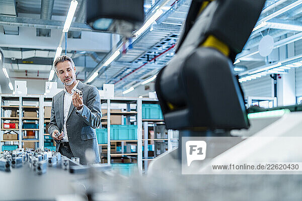 Man in a production hall with industrial robot in a business setting