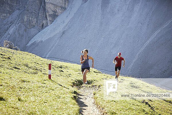 Man and woman running uphill in the mountains
