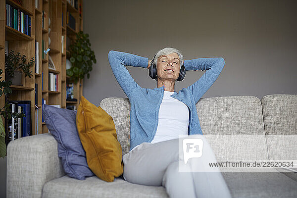 Senior woman relaxing at home listening to music with headphones