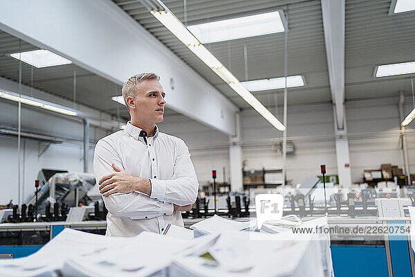 Man in white shirt in a factory looking around