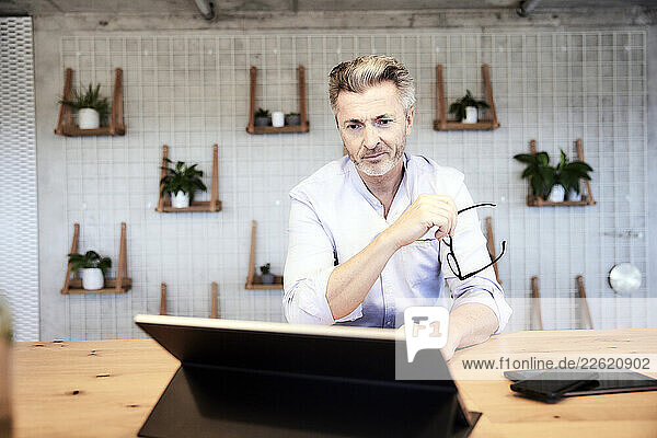 Mature businessman using digital tablet while working at home
