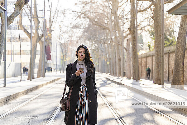 Young woman using smartphone on tram line