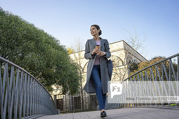 Female entrepreneur looking away while walking on footbridge during autumn