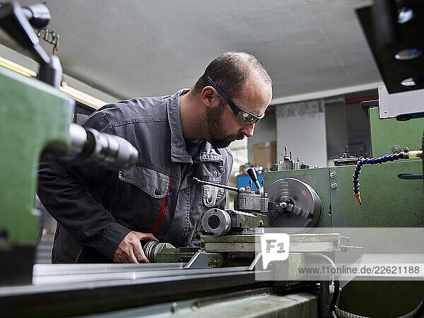 Metal construction technician working at a lathe in his workshop