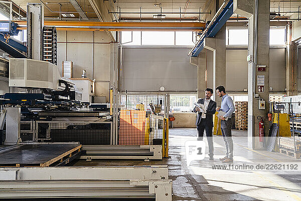 Businessmen examining automated machine while standing at factory