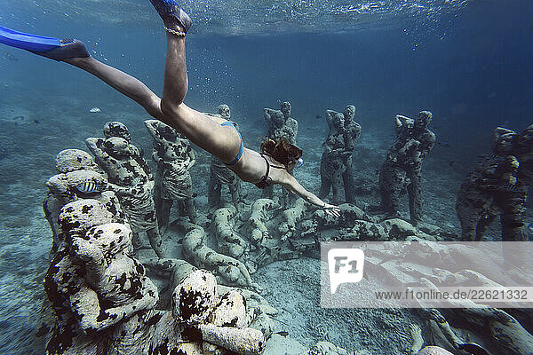 Woman swimming near underwater sculpture made by Jason deCaires Taylor  Gili Meno island  Bali  Indonesia