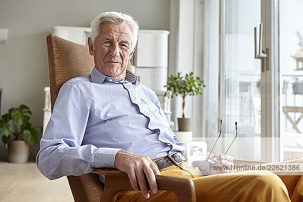Senior man relaxing in a chair at home  smiling and holding glasses