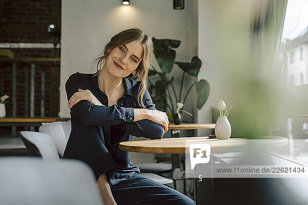 Woman sitting in a café smiling and looking at the camera