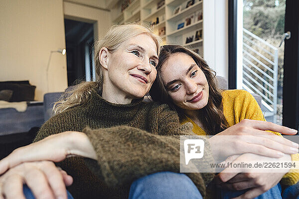 Mother and daughter sitting together at home sharing a moment of affection