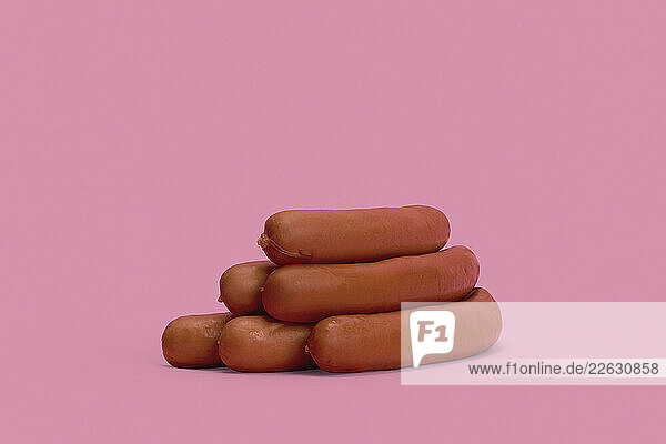 Bavarian sausages stacked on pink background