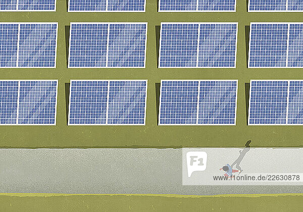 View from above man jogging along solar panels in field