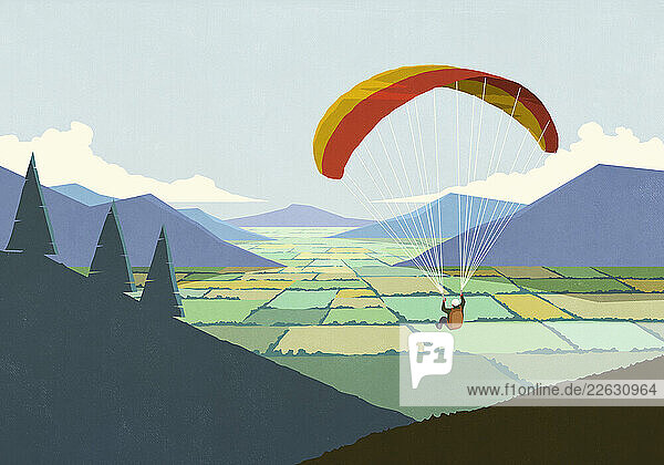 Parachuter descending over scenic rural mountain valley landscape