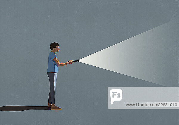 Man holding bright flashlight in dark