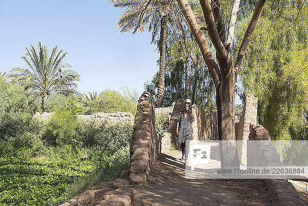 Woman walking on a path in the Date palm groves in the oasis of AlUla  Medina Province  Saudi Arabia