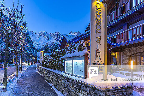 View of town centre and snow covered mountains in background at dusk  Courmayeur  Aosta Valley  Italian Alps  Italy