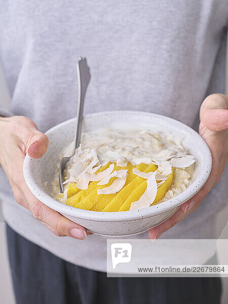 Overnight-Oats mit frisch geschnittenen Mangoscheiben und Kokosflocken