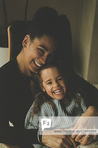 Happy woman playing with daughter at home