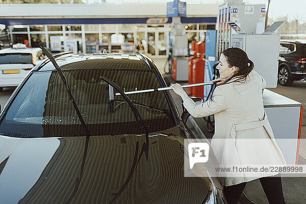 High angle view of woman cleaning windshield of car with squeegee