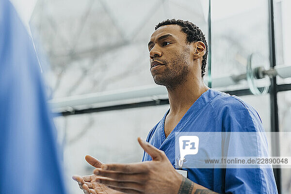 Low angle view of male physician explaining during meeting in hospital