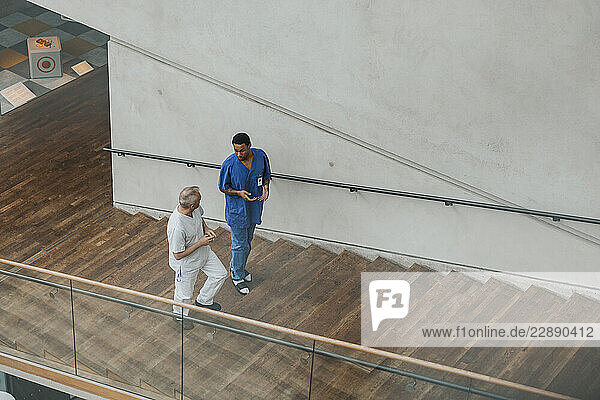 High angle view of male medical professionals discussing with each other while moving up steps in hospital building