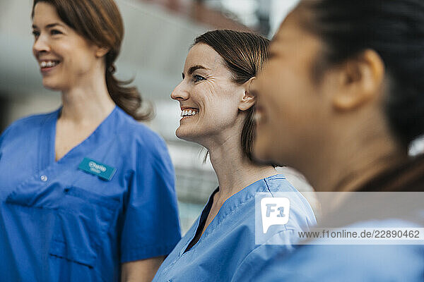 Happy female healthcare worker in meeting with team at hospital
