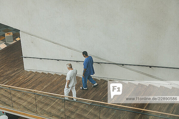 High angle view of male physicians wearing medical scrubs moving down steps in hospital building