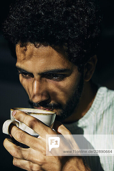 Sunlight shining on thoughtful man drinking coffee