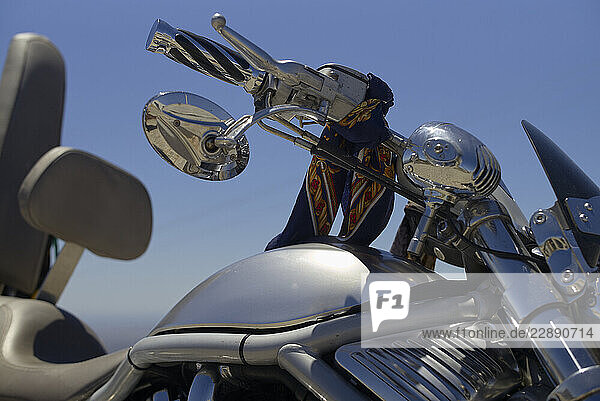 Chrome motorcycle with ornate handlebars and a blue bandana under clear blue sky. Portugal