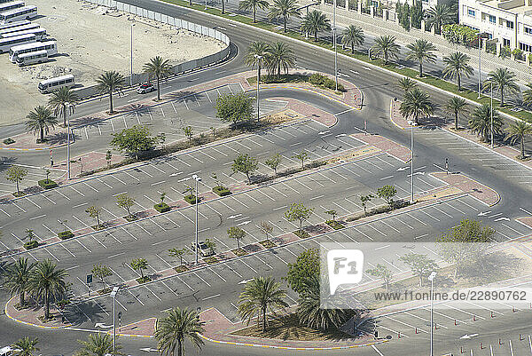 Aerial view of an empty parking lot with scattered palm trees and surrounding roads. Abu Dhabi  UAE