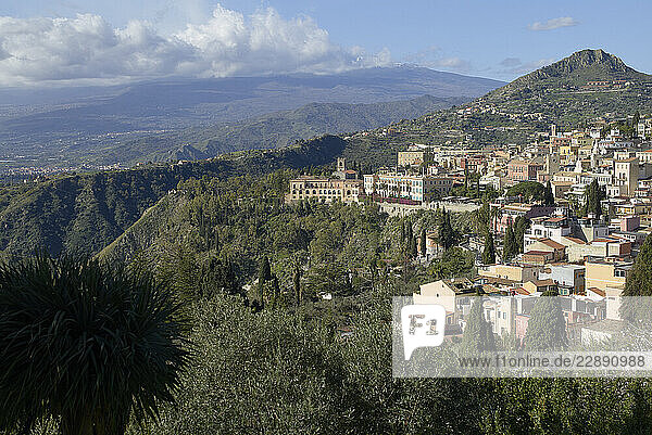 Scenic hillside townscape with distant mountains under a partly cloudy sky. Sicily  Italy