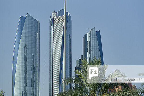 Tall modern skyscrapers with reflective glass facades against a clear blue sky and palm trees. Abu Dhabi  UAE