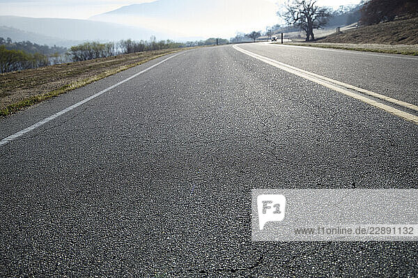 A winding road stretches into the distance with cracked asphalt and a misty landscape. Los Angeles  USA