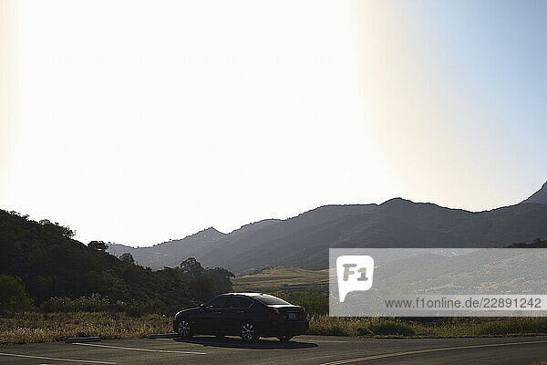 A car is parked on a scenic roadside with mountains in the background under a clear sky. Los Angeles  USA