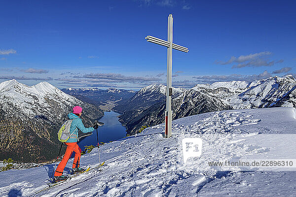 Woman back country skiing by summit cross at Baerenkopf near Achensee  Karwendel Mountains  Tyrol  Austria