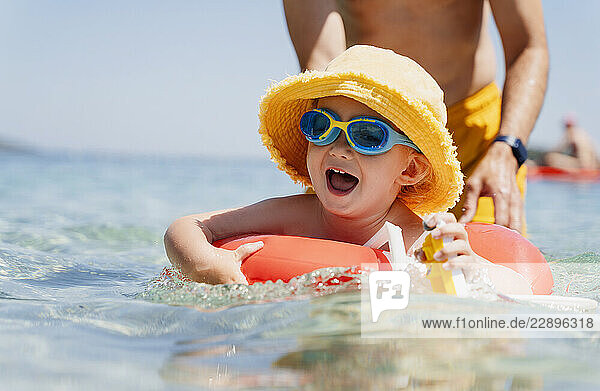 Boy learning to swim with dad during a summer family vacation at the beach