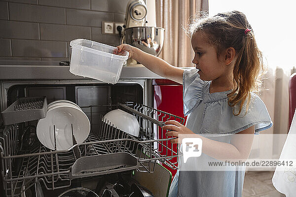 Child helping with dishwasher in the kitchen during the day