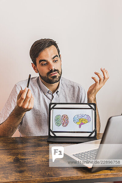 Mental health professional explaining human brain diagram during video call through laptop