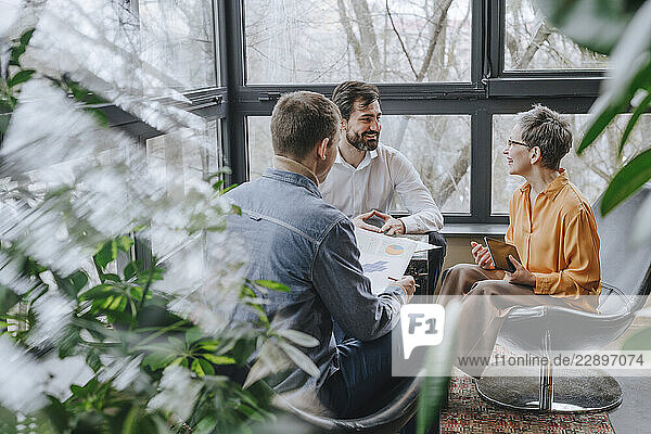 Smiling businessman having discussion with colleagues in office
