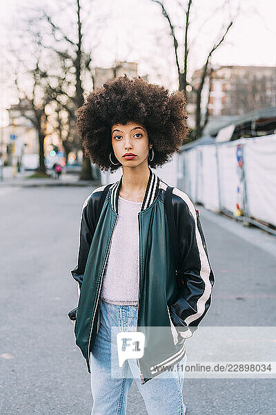 Afro hairstyle woman standing with hands in pockets on road