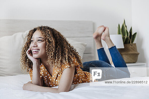 Beautiful young woman smiling while lying on bed at home