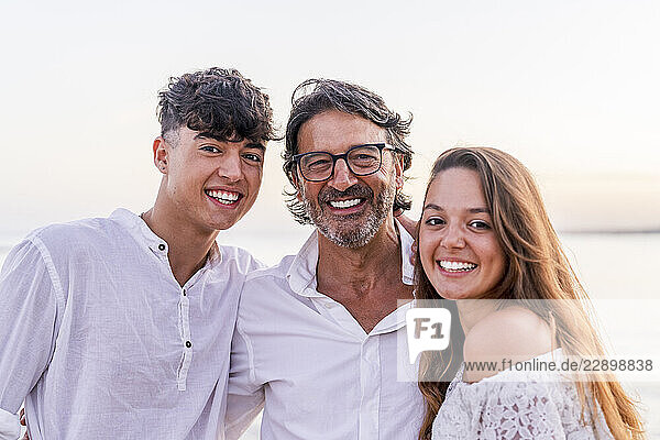 Happy father with son and daughter at beach during sunset