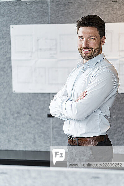 Male entrepreneur with arms crossed standing in office