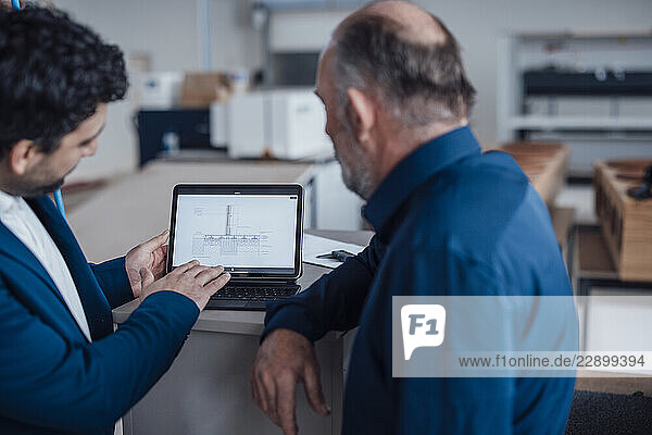 Engineers discussing a project on a laptop in an office setting