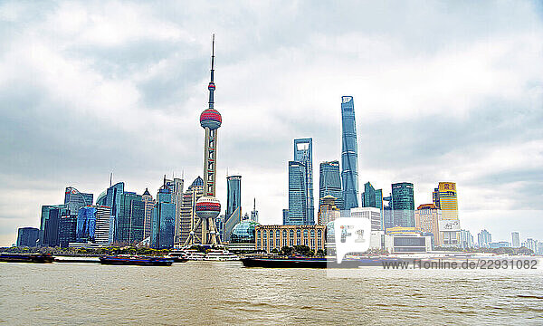 The iconic skyline of Lujiazui along the busy Huangpu River with never ending convoy of cargo vessels  Shanghai  China.