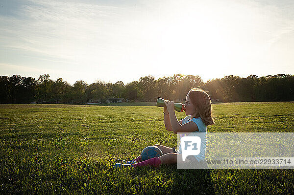 Young girl taking water break during soccer practicce sunny day