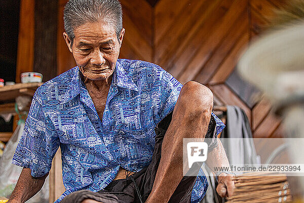Elderly Thai artisan working with traditional tools