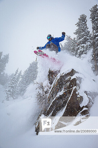 A man skiing off a cliff into fresh snow. Snowbird Utah