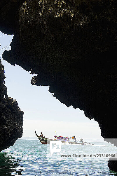 View of a speeding longtail boat framed by rock formations on January 7  2009 in Ao Nang  Thailand.